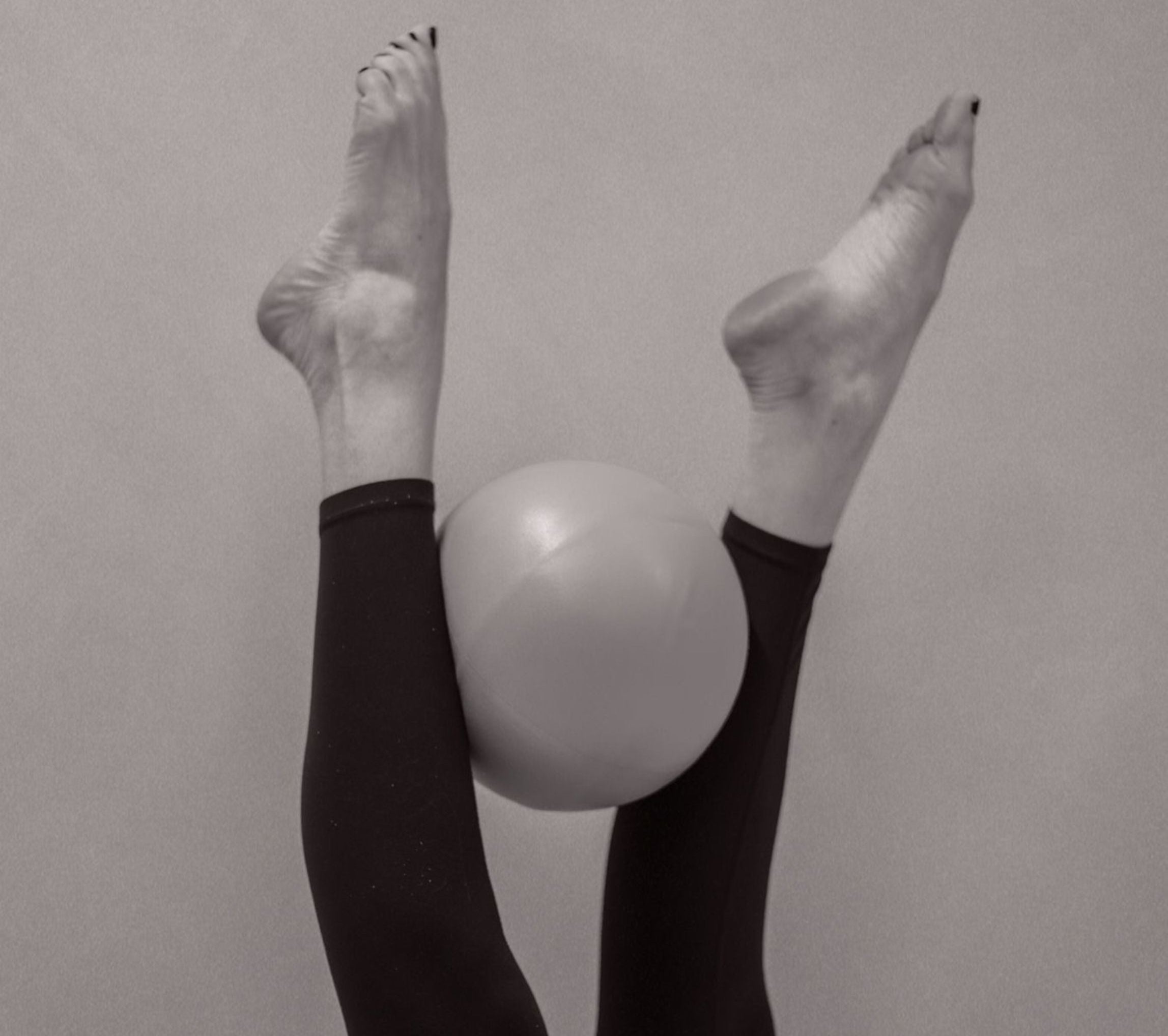 Person wearing black leggings with a white ball between their legs against a plain background